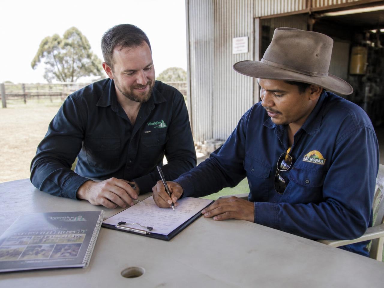 Farm coordinator and worker completing induction paperwork beside a shed in rural Victoria